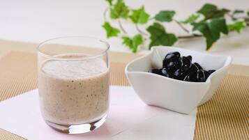 Ett glas smoothie står på en servett, och i bakgrunden syns en skål med svarta oliver.