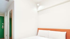 A hotel room with a large bed, a wooden headboard, and a green door.