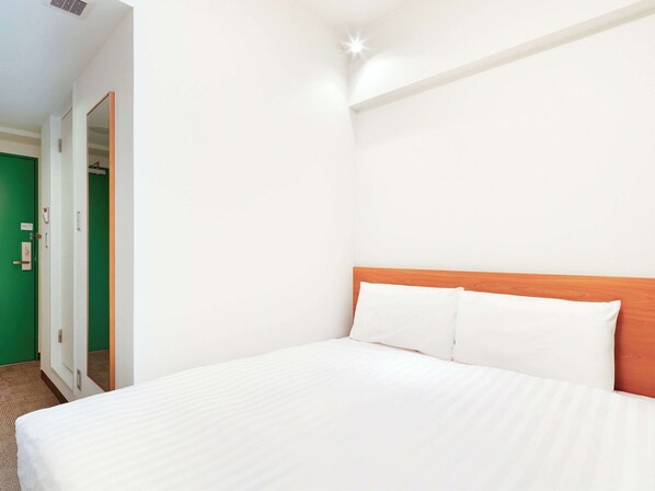 A hotel room with a large bed, a wooden headboard, and a green door. - Comfort Inn Himeji Yumesakibashi (Himeji)