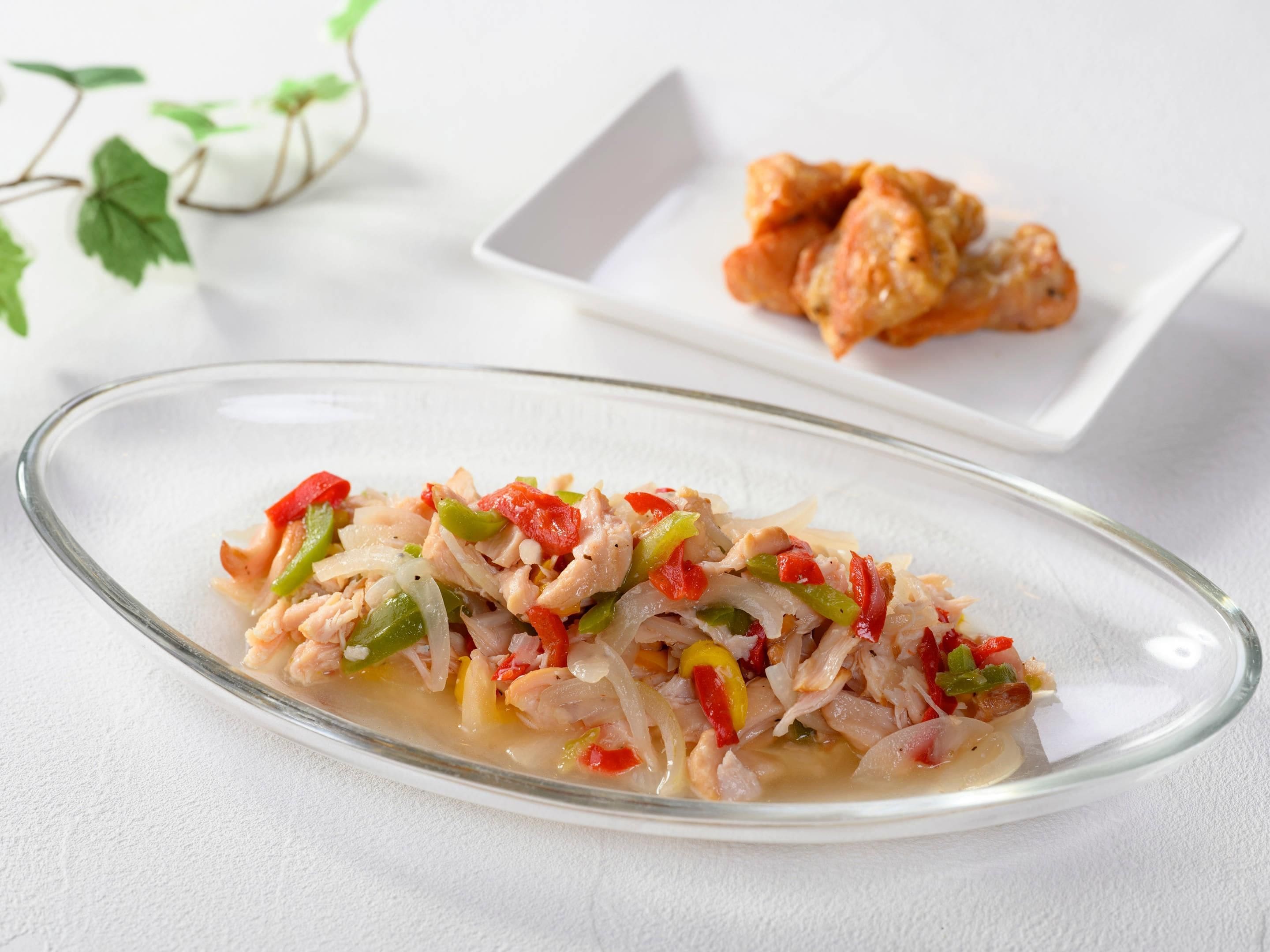 A clear glass dish with a seafood salad, a white plate with fried items, and a white tablecloth.