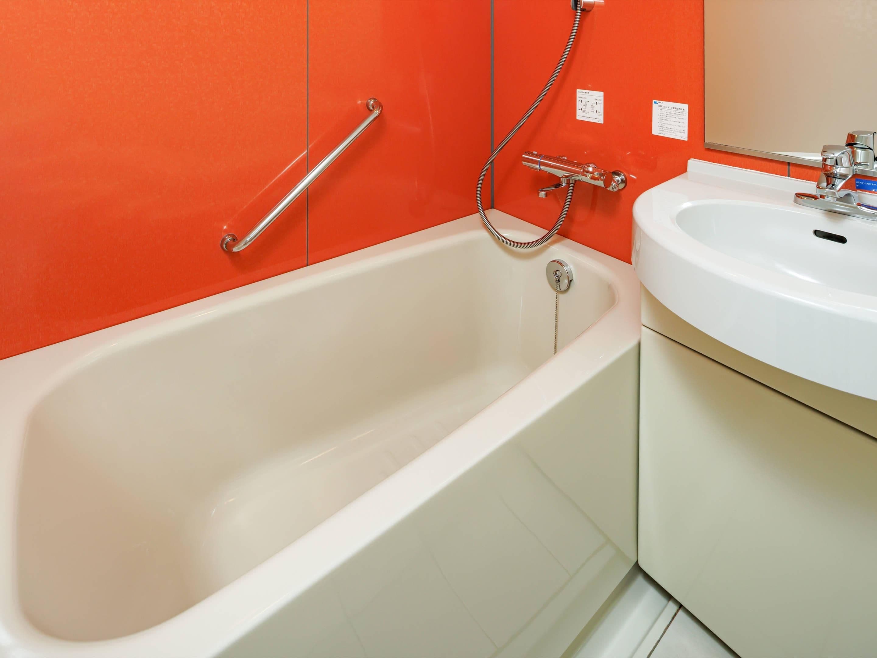 A bathroom with a bathtub, a white sink, and a shower with a handheld showerhead.