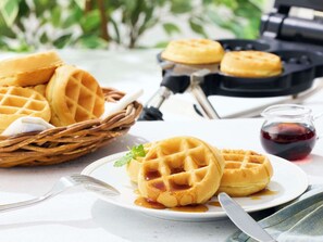 Waffles on a plate with syrup, a waffle maker, and a basket of waffles in the background. - Comfort Inn Fukushima Nishi Inter (Fukushima)