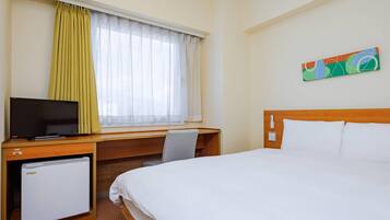 Una habitación de hotel con una cama, un escritorio con televisor, un refrigerador pequeño, una ventana con cortinas y un cuadro colgado en la pared.