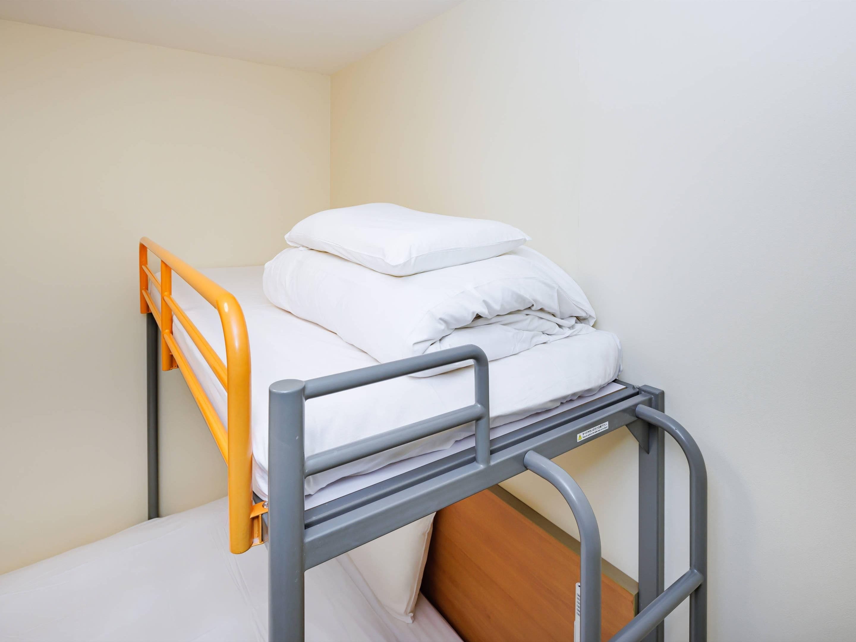 Una cama litera con una base inferior de madera y una superior naranja.