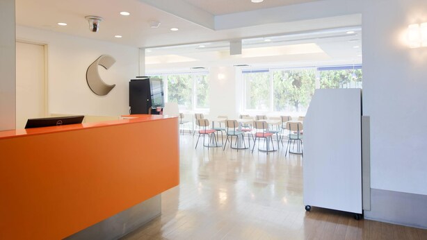 A spacious, well-lit reception area with a modern design, featuring a reception desk, a large window, and a seating area with chairs. - Comfort Inn Kumamoto Miyukifueda (Kumamoto)