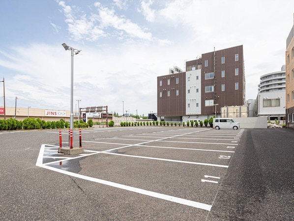 A parking lot with marked spaces, a white van, and a building with multiple floors and windows.