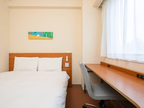 Une chambre d’hôtel avec un lit, un bureau et une fenêtre avec des rideaux blancs.