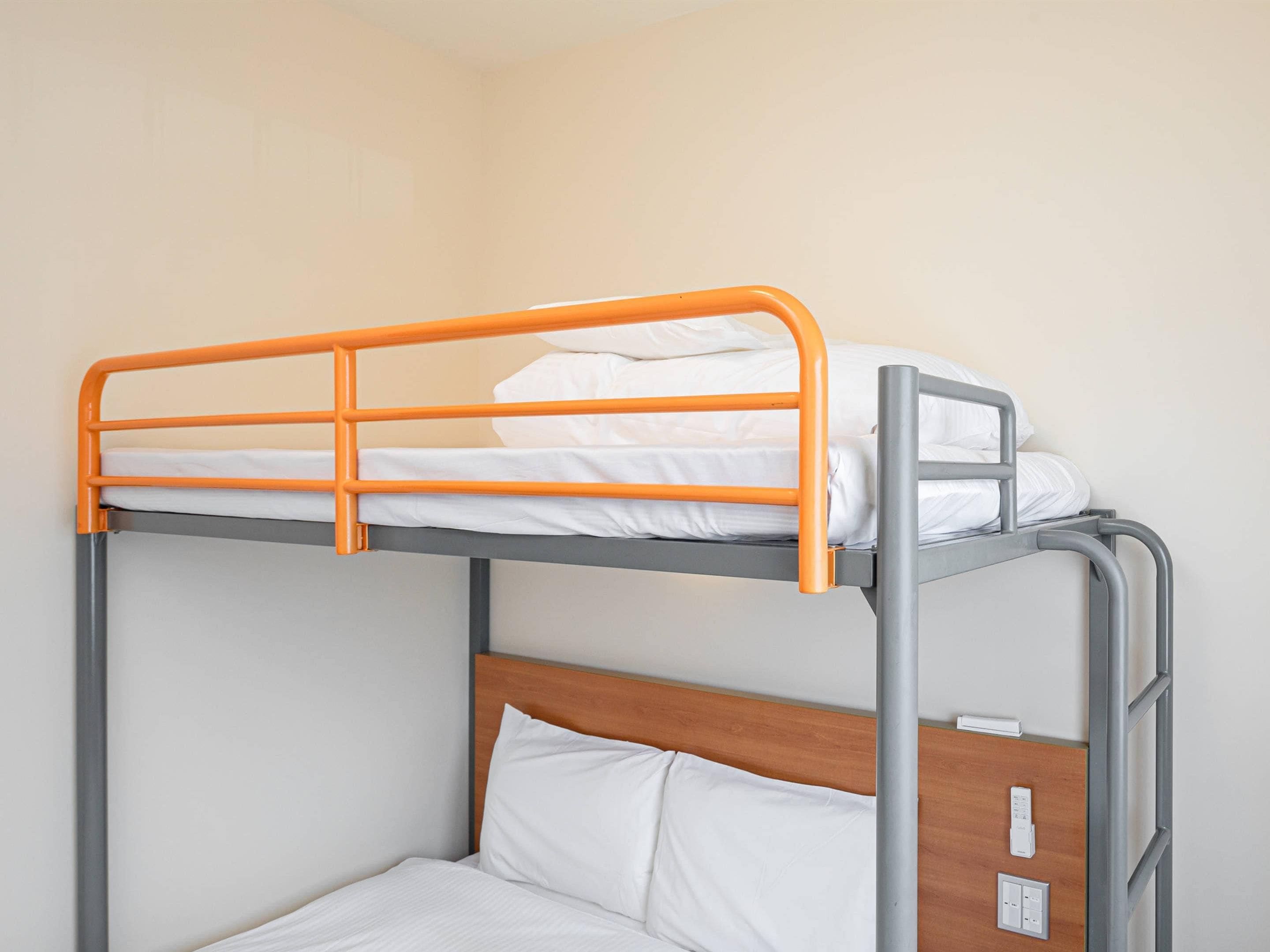 A bunk bed with an orange frame and a wooden headboard.