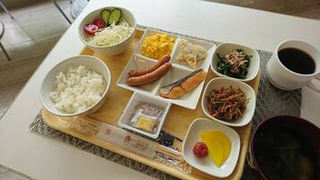 Bandeja de comida con arroz, salchichas, huevos, verduras y una taza de café.
