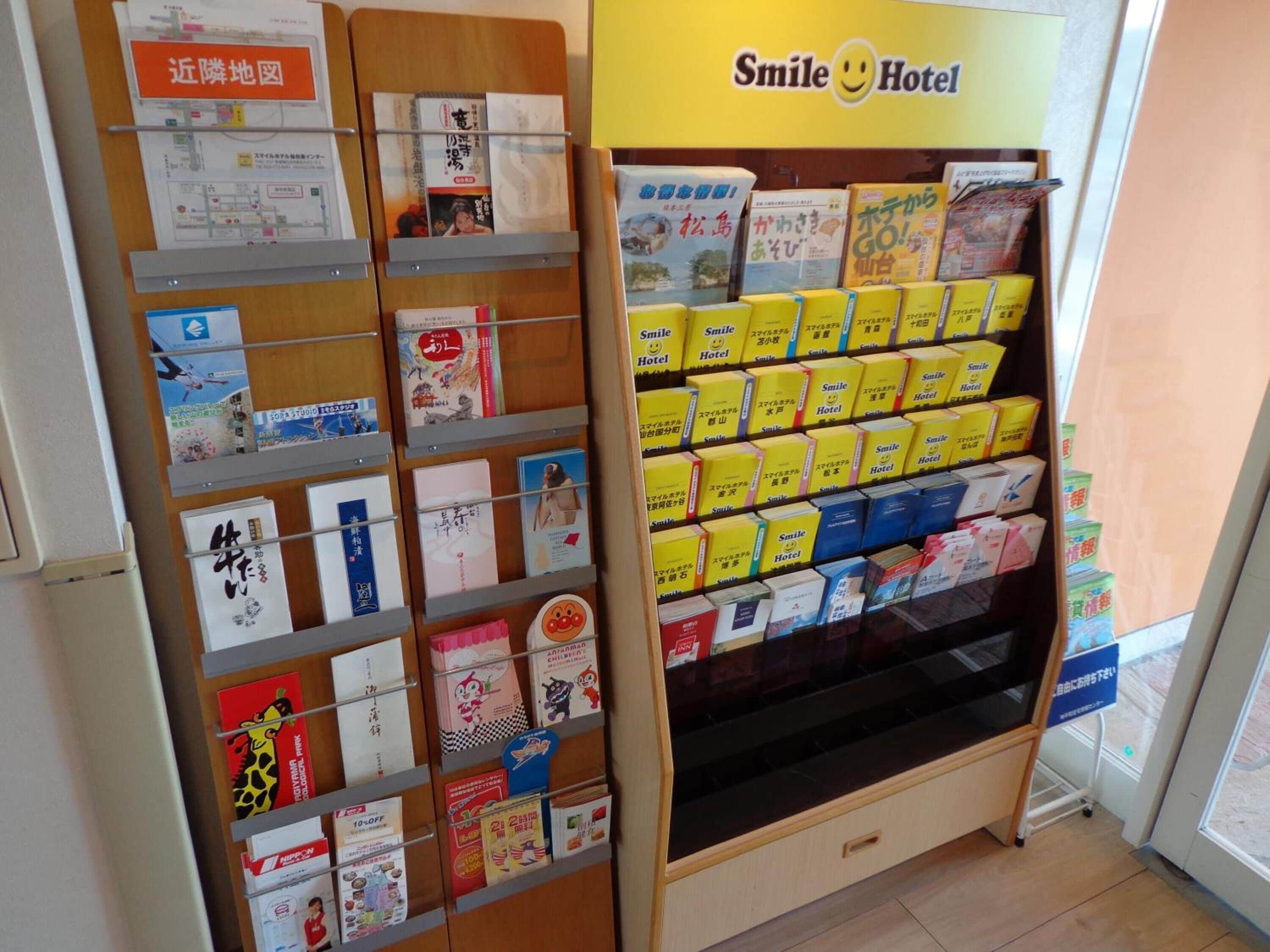 A hotel reception area with a display of postcards and a Smile Hotel sign.