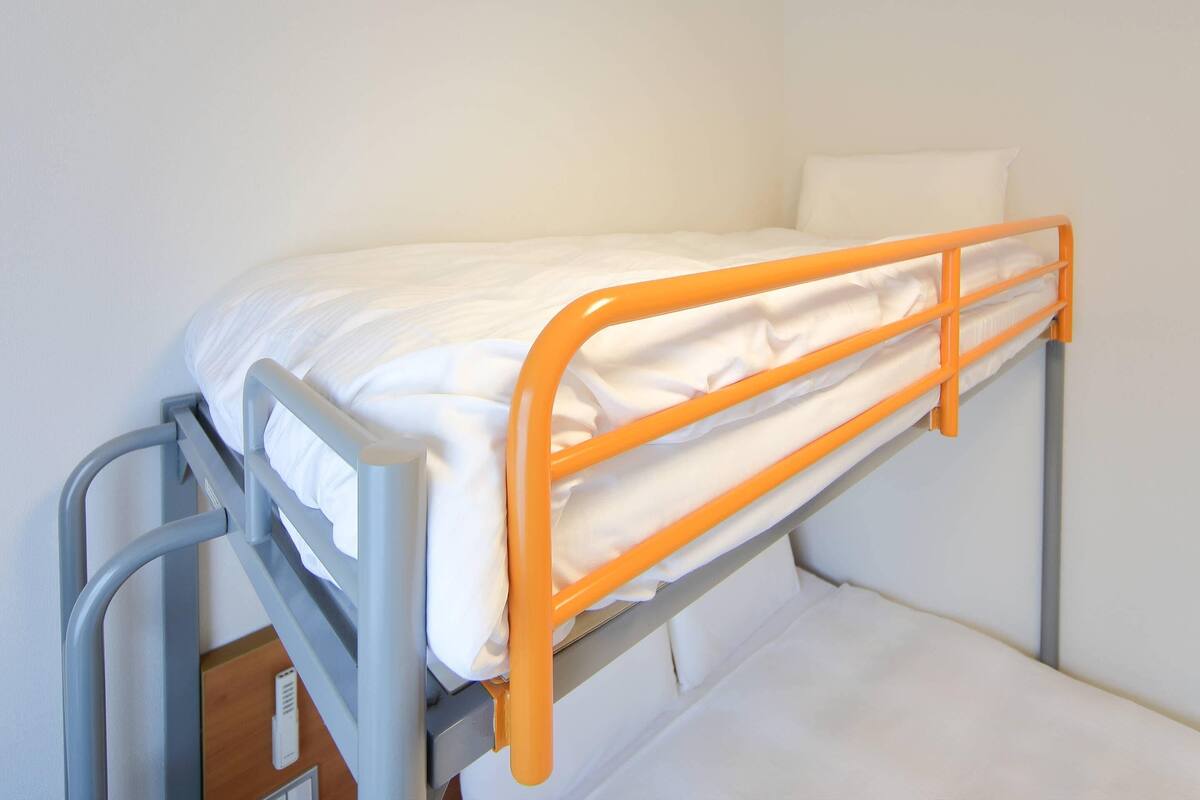 Ein Etagenbett mit orangefarbener Umrandung und weißer Bettwäsche.