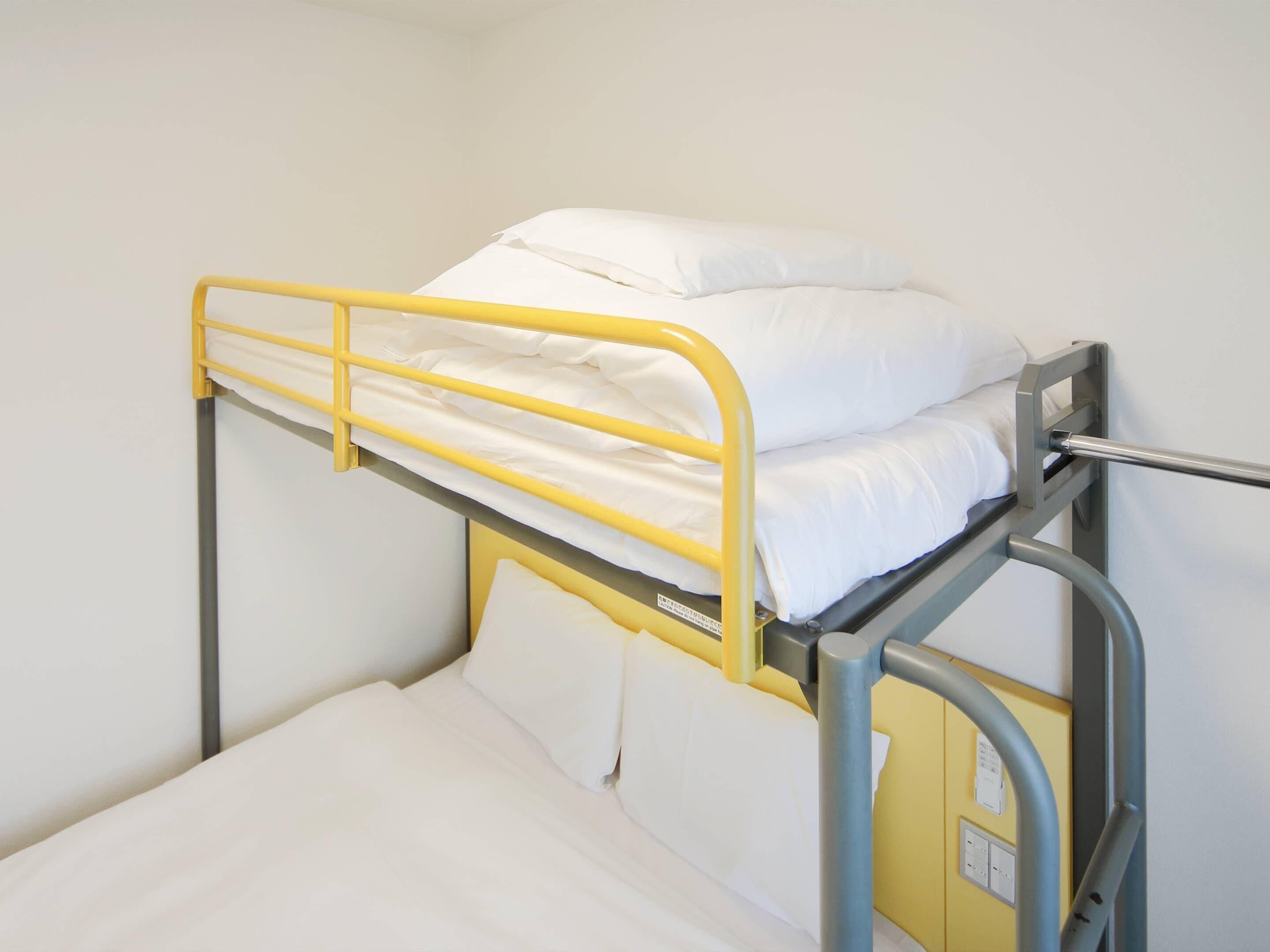 Una cama litera con estructura amarilla y ropa de cama blanca.