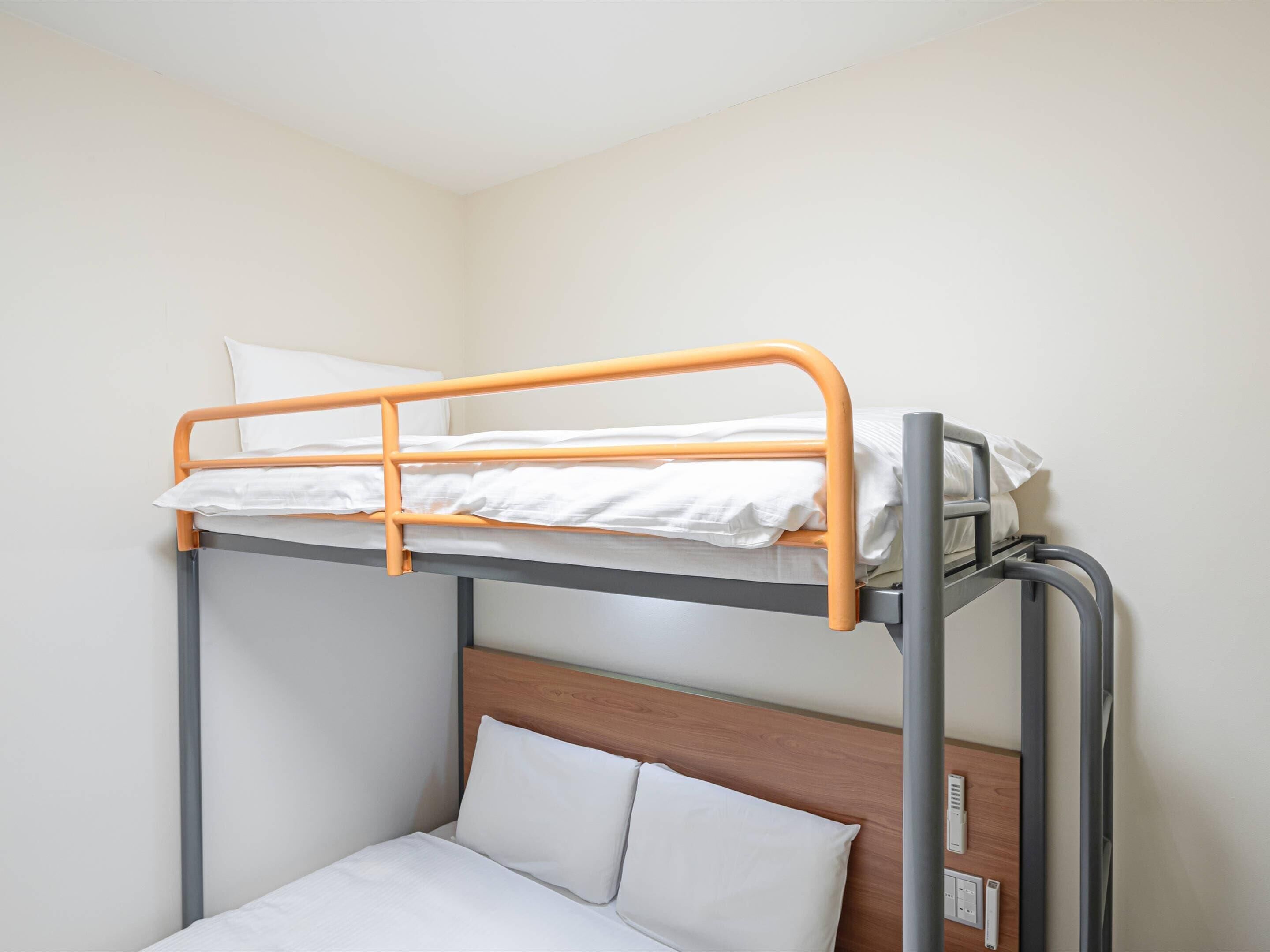 A bunk bed with a wooden headboard and a lower single bed.