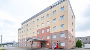 Een meerlaags hotel met een plat dak, een Coca-Cola automaat en een bank buiten.