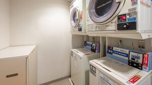 Een wasserette met meerdere wasmachines en drogers, waaronder een voorlader wasmachine en een droger met bovenlader.