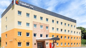 Ein Comfort Inn Hotel mit modernem Design, mit flachem Dach, mehreren Fenstern und einer Coca-Cola-Getränkeautomat.