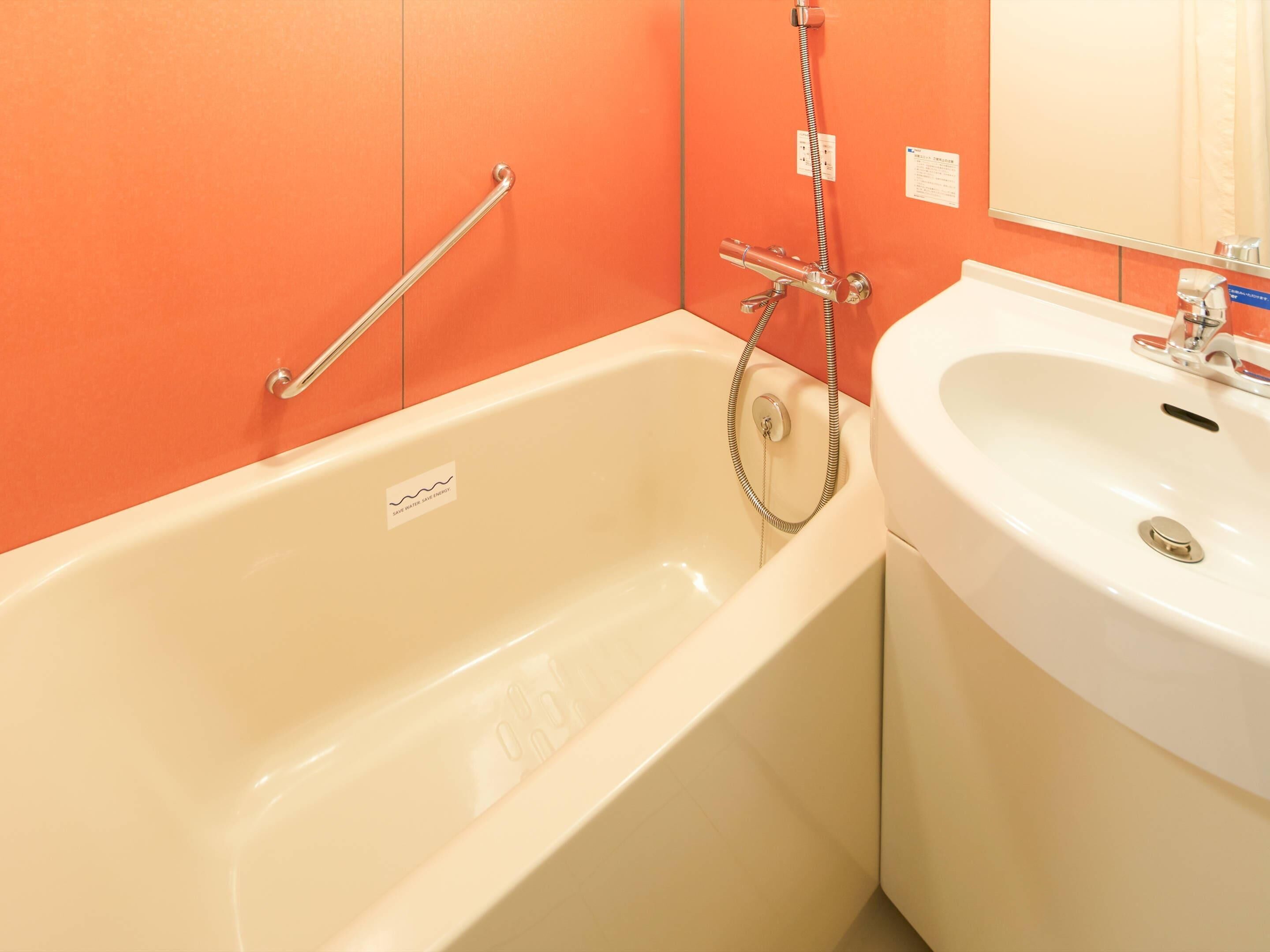 A bathroom with a bathtub, a sink, and a handrail.