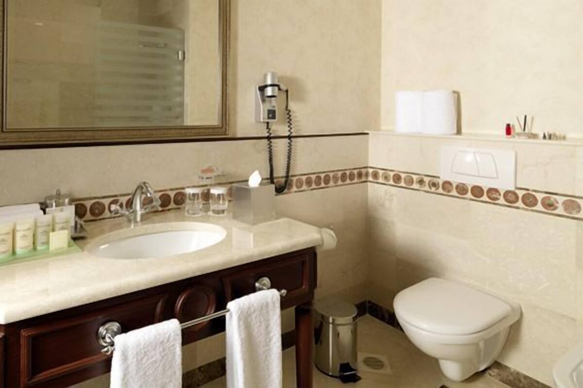 Un baño con lavamanos, espejo e inodoro.