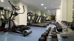 Un gimnasio con cintas de correr, máquinas de remo y mancuernas.