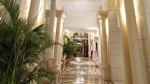 Un pasillo con columnas, plantas en macetas y piso pulido.