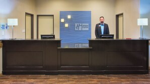 A hotel reception desk with a nameplate for Holiday Inn Express, two receptionists, and a check-in counter. - Holiday Inn Express Hotel & Suites Alvarado by IHG (Alvarado)