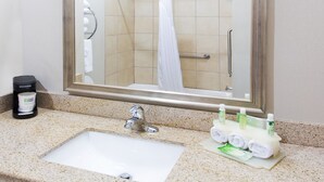 Ein Badezimmer mit Waschbecken, Spiegel, Handtuchhalter und Pflegeprodukten.