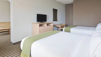 Una habitación de hotel con dos camas, un escritorio con televisor, una silla y una mesita.