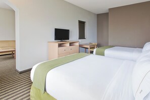 A hotel room with two beds, a desk with a television, a chair, and a small table.
