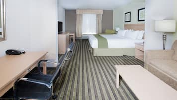 Une chambre d’hôtel avec un lit, un bureau, une chaise, un canapé et une lampe.