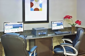 Una mesa de recepción con dos monitores de computadora, una impresora y dos sillas de oficina.