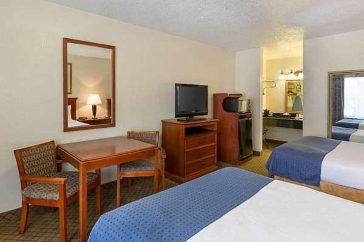 Une chambre d’hôtel équipée d’un bureau, de deux lits, d’une télévision et d’un miroir.