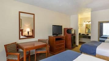 A hotel room with a desk, two beds, a television, and a mirror.