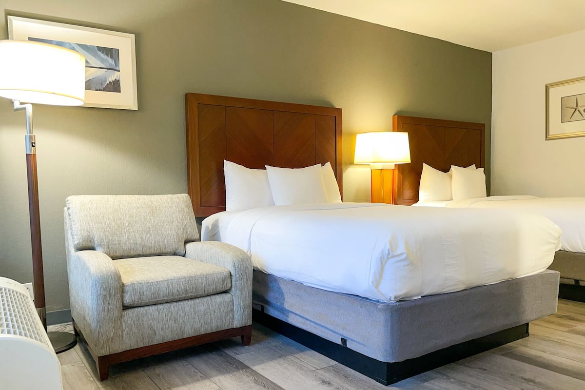 Une chambre d’hôtel avec un grand lit, une chaise, une lampe et un tableau encadré au mur.