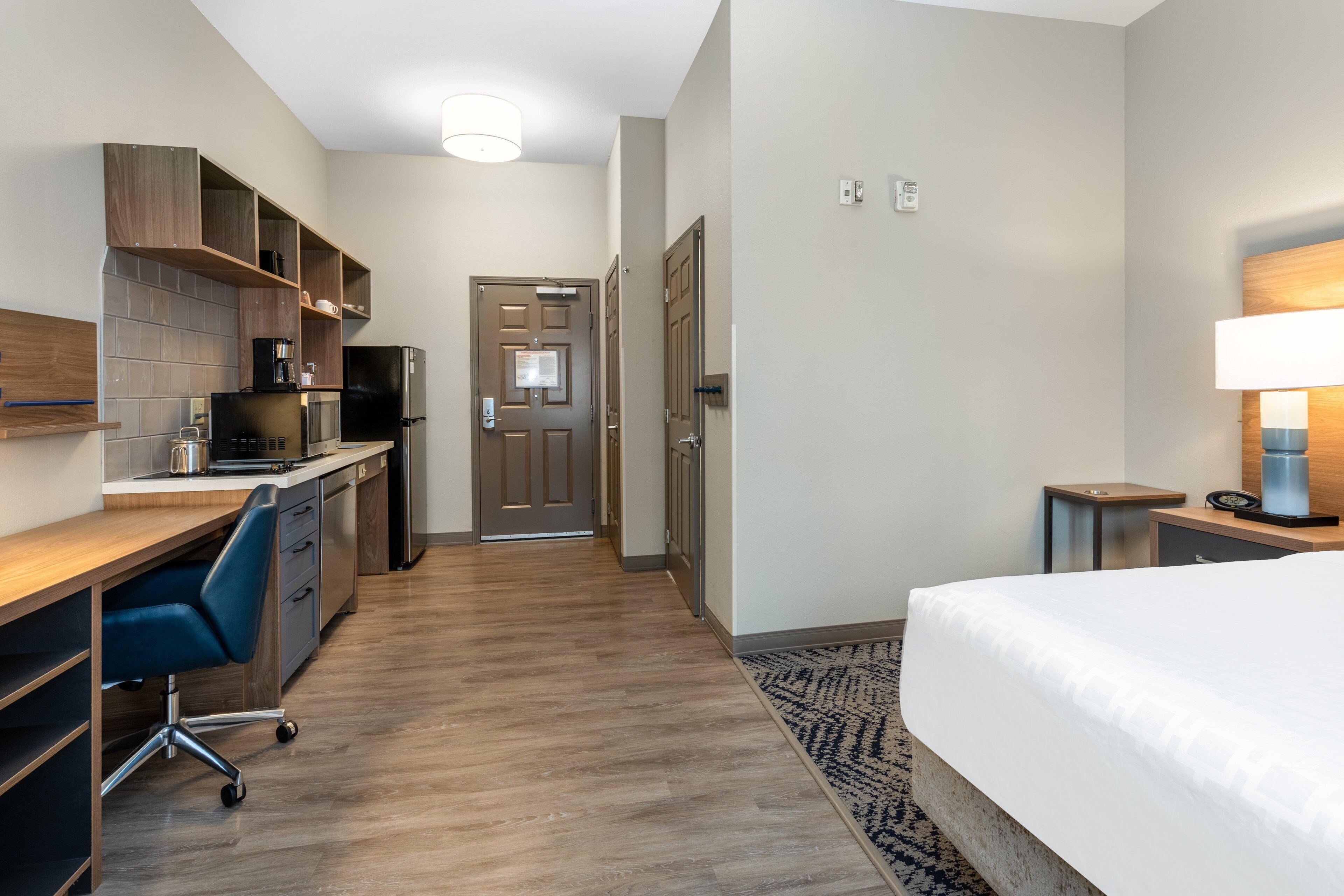 Habitación de hotel con cama, escritorio, kitchenette y baño.