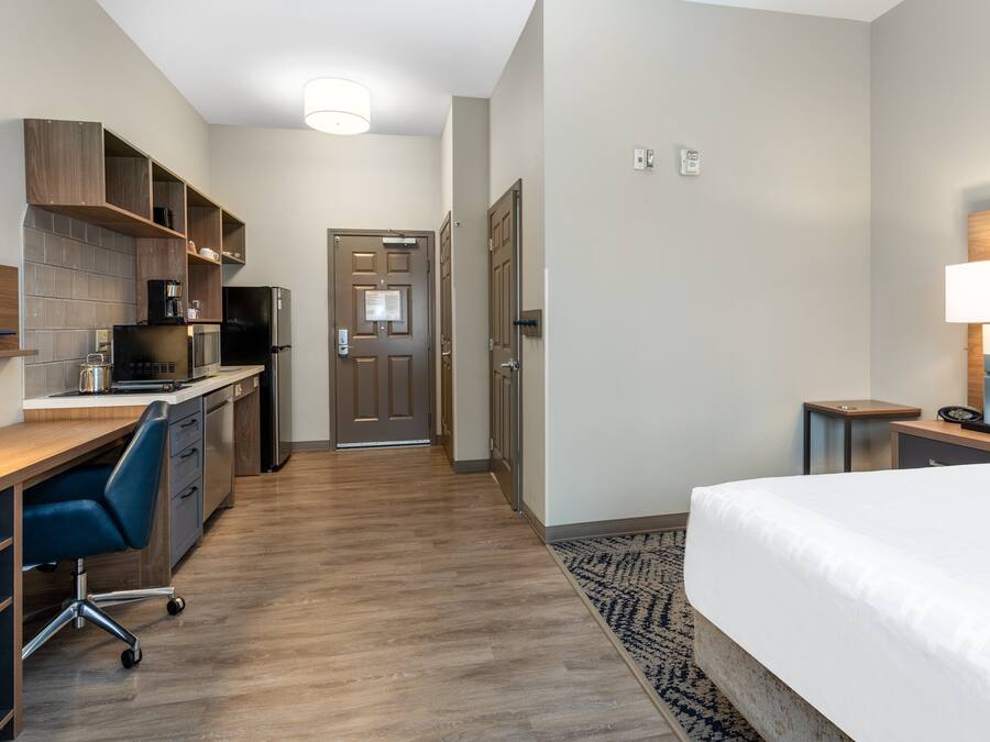 Habitación de hotel con cama, escritorio, kitchenette y baño.