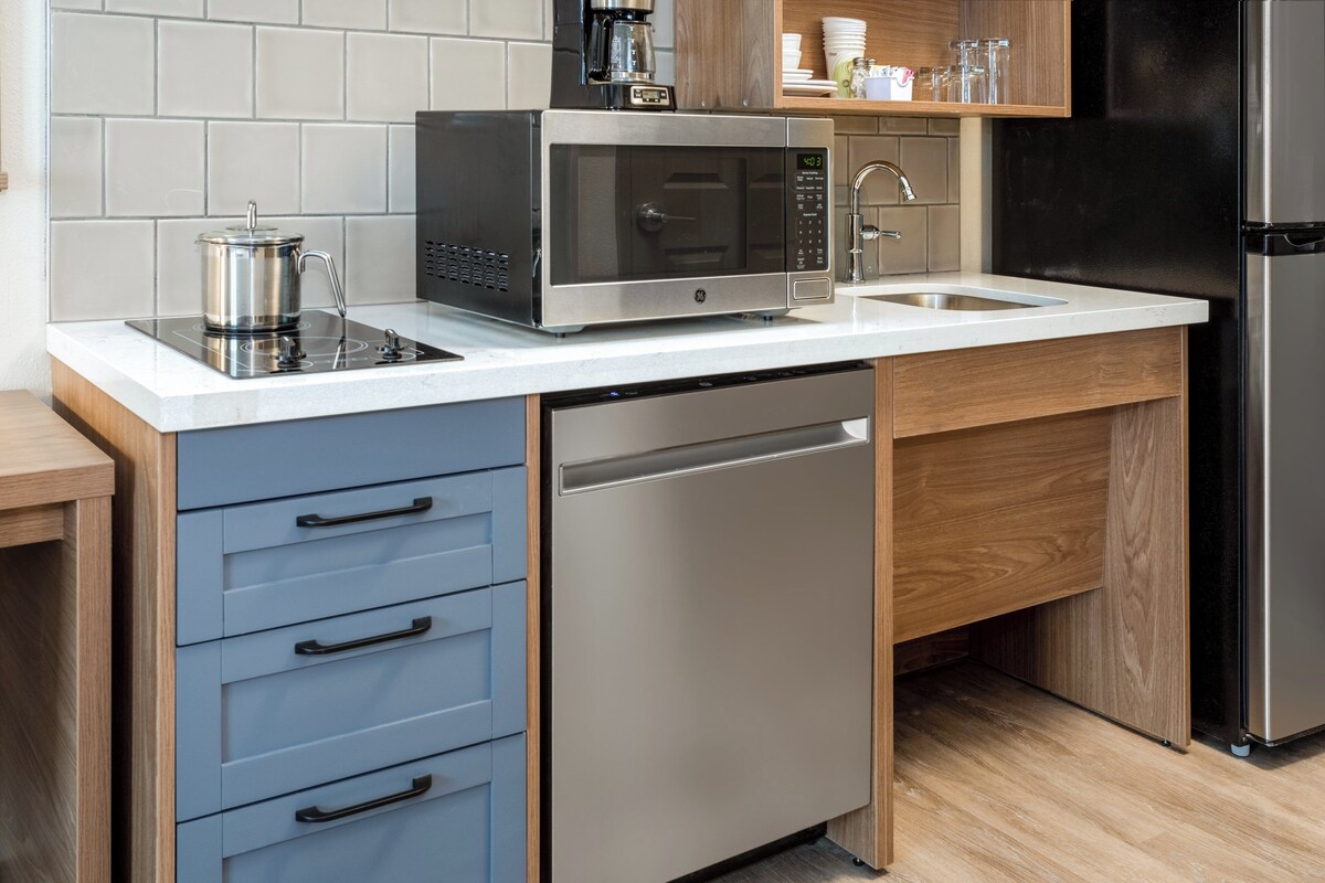 A modern kitchen with a built-in microwave, a coffee maker, a sink, and a dishwasher.