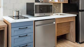 Una cocina moderna con microondas integrado, cafetera, lavaplatos y fregadero.