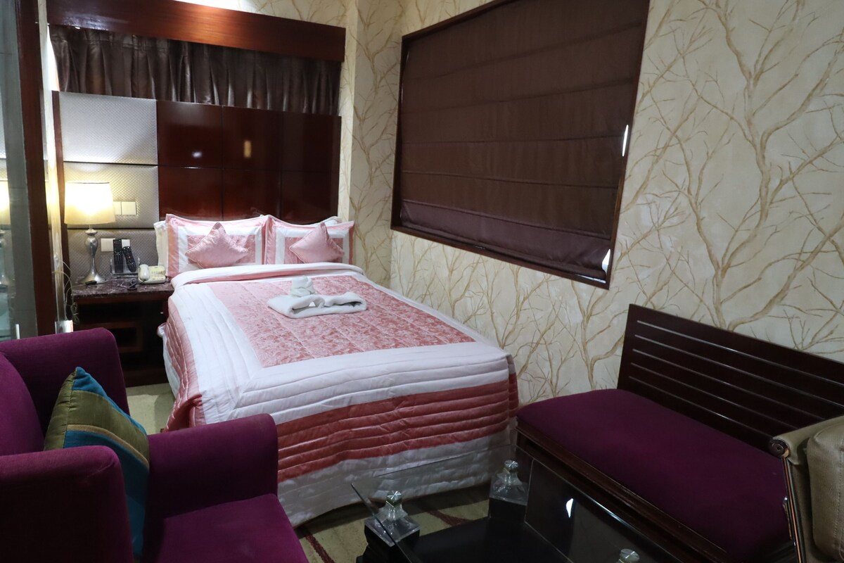A hotel room with a bed, a desk, a chair, and a sofa.