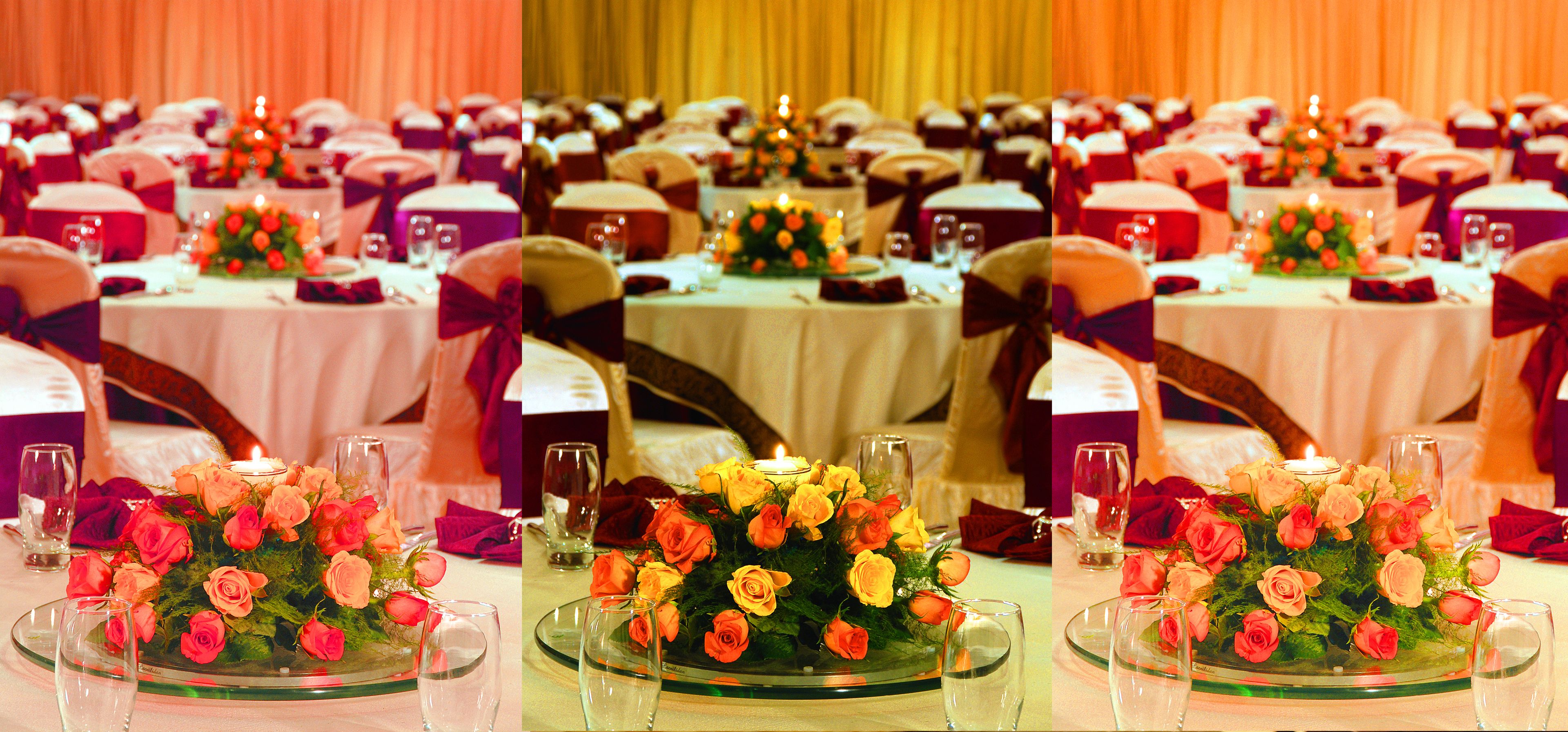 A banquet hall with round tables, each adorned with floral centerpieces and glassware.