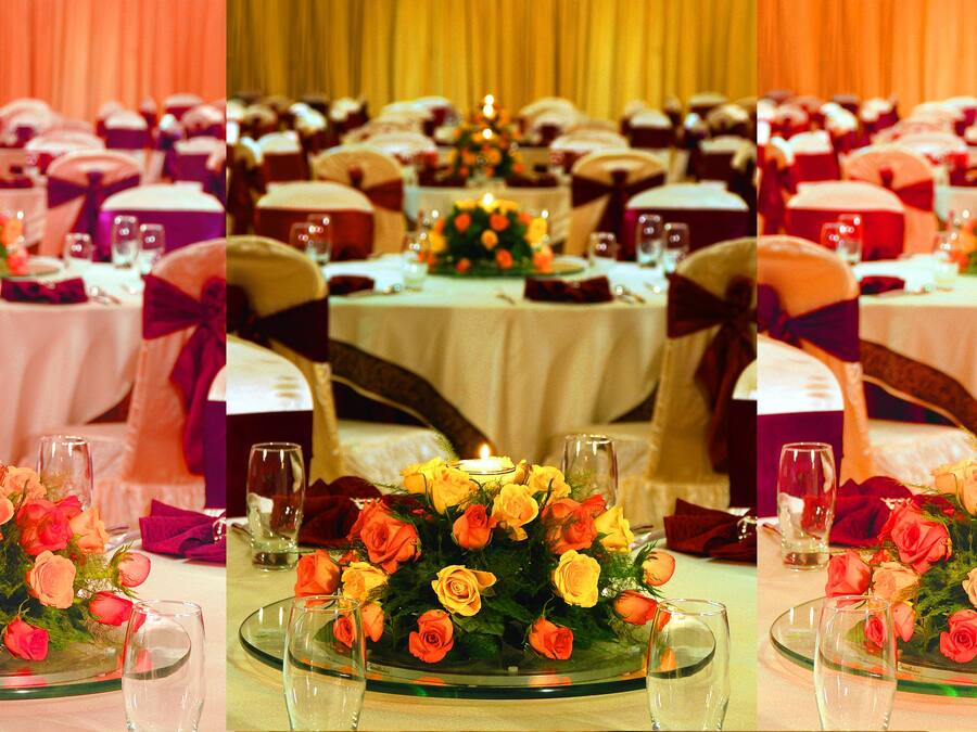 A banquet hall with round tables, each adorned with floral centerpieces and glassware.