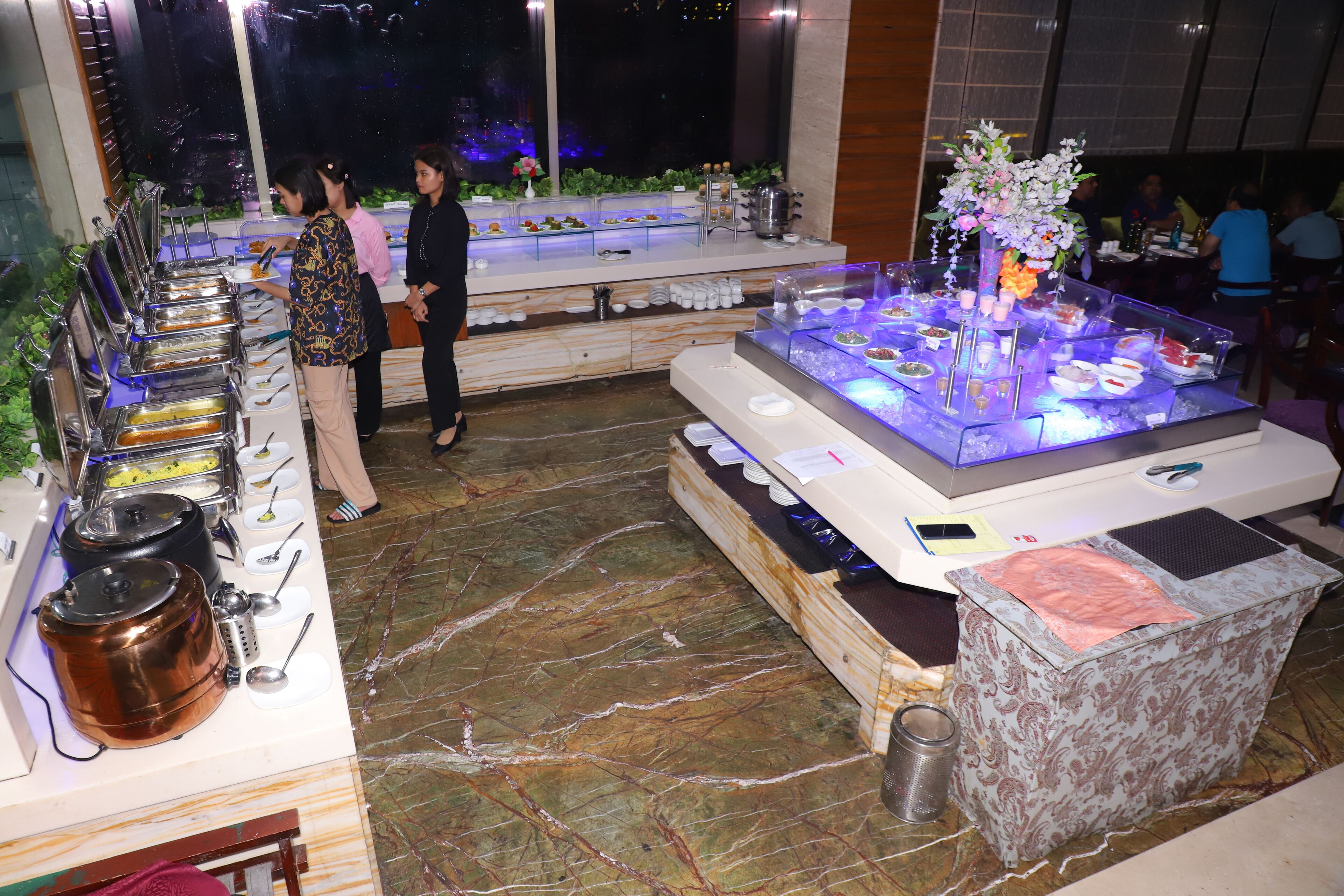 Disposição de buffet com diferentes estações de comida e uma peça decorativa central.