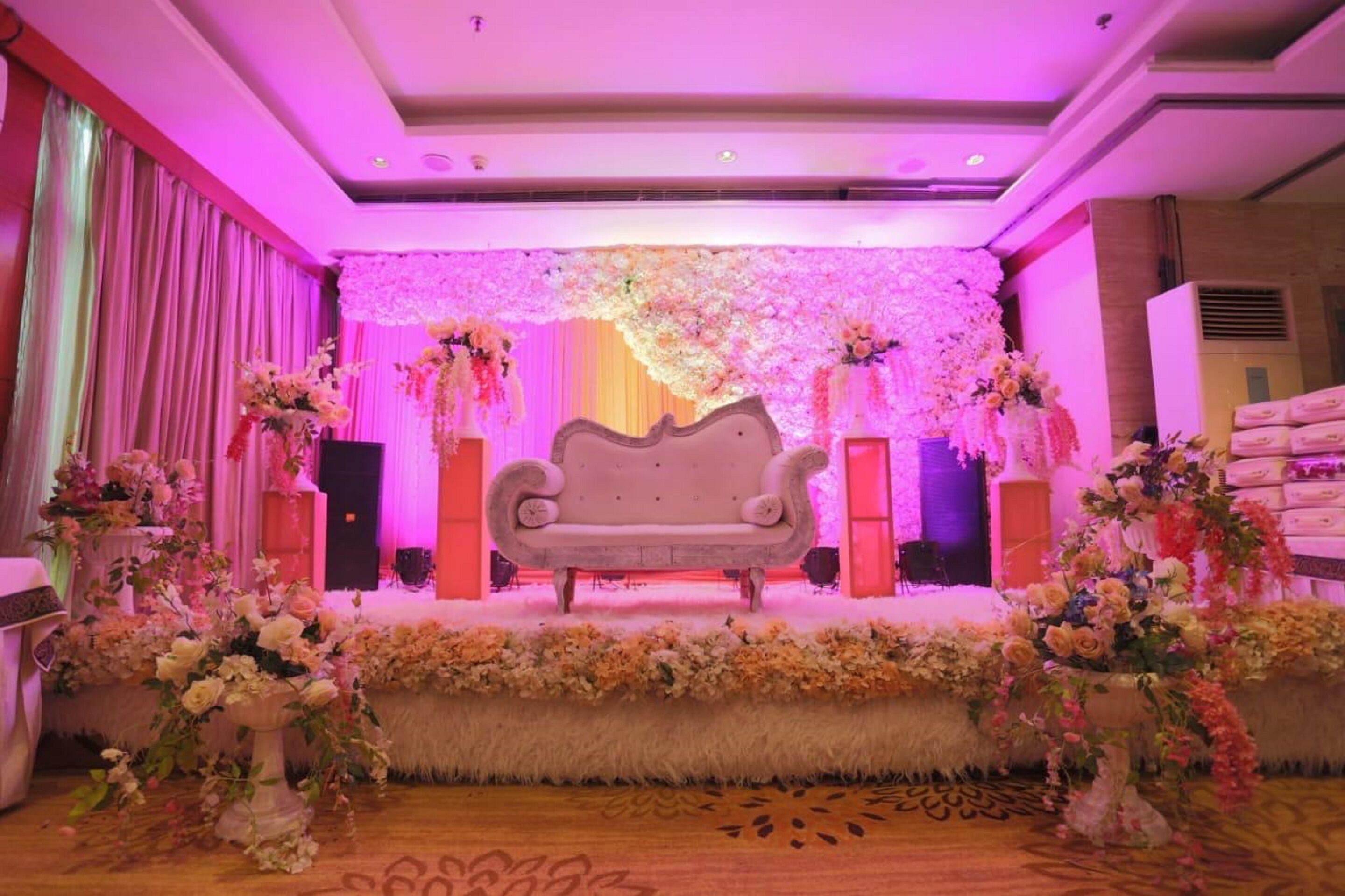 Une scène avec un canapé, des compositions florales et un décor composé de fleurs roses et blanches.