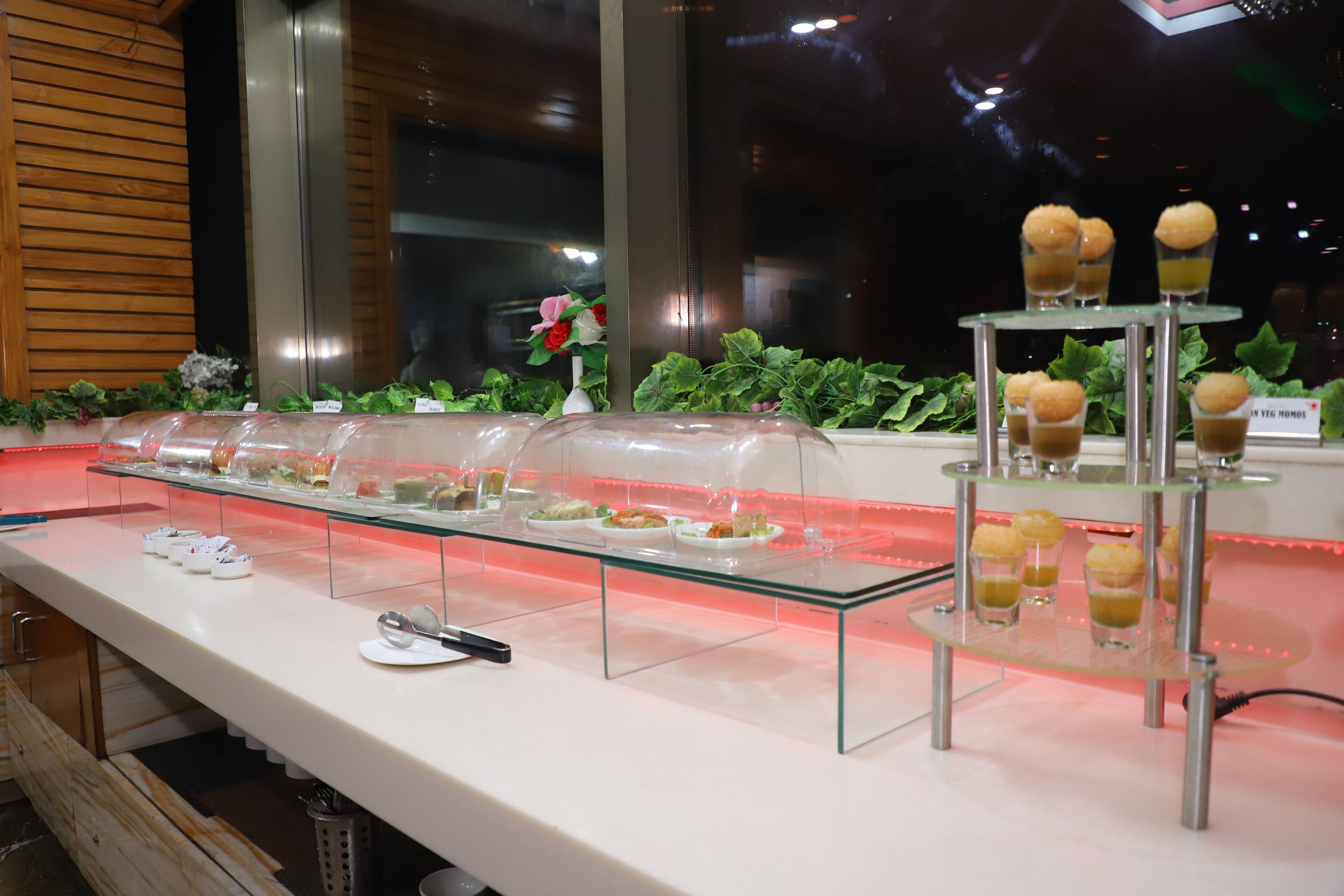A buffet setup with various food items displayed on glass stands and in clear containers.