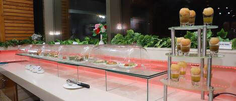 A buffet setup with various food items displayed on glass stands and in clear containers.