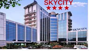 A multi-story hotel with a modern glass facade, balconies, and a clear sky. - Skycity Hotel (Gurugram)