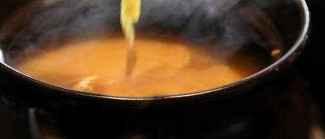 A ladle lifting a thick, orange-colored soup from a pot.