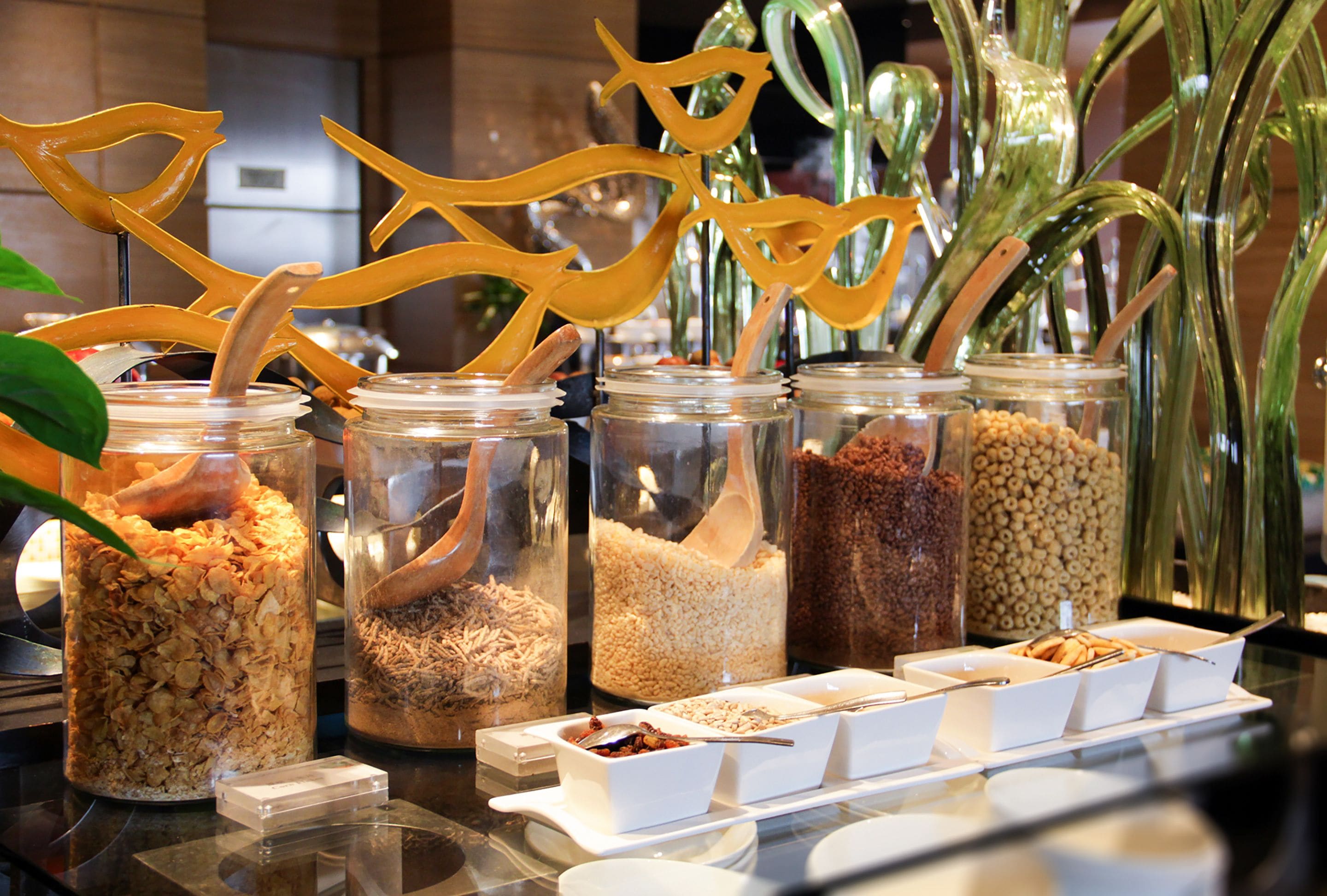 A breakfast buffet with various food items in jars and bowls, arranged on a table.