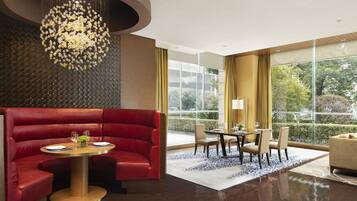 A modern hotel lobby with a red leather sofa, a round dining table, and a chandelier.