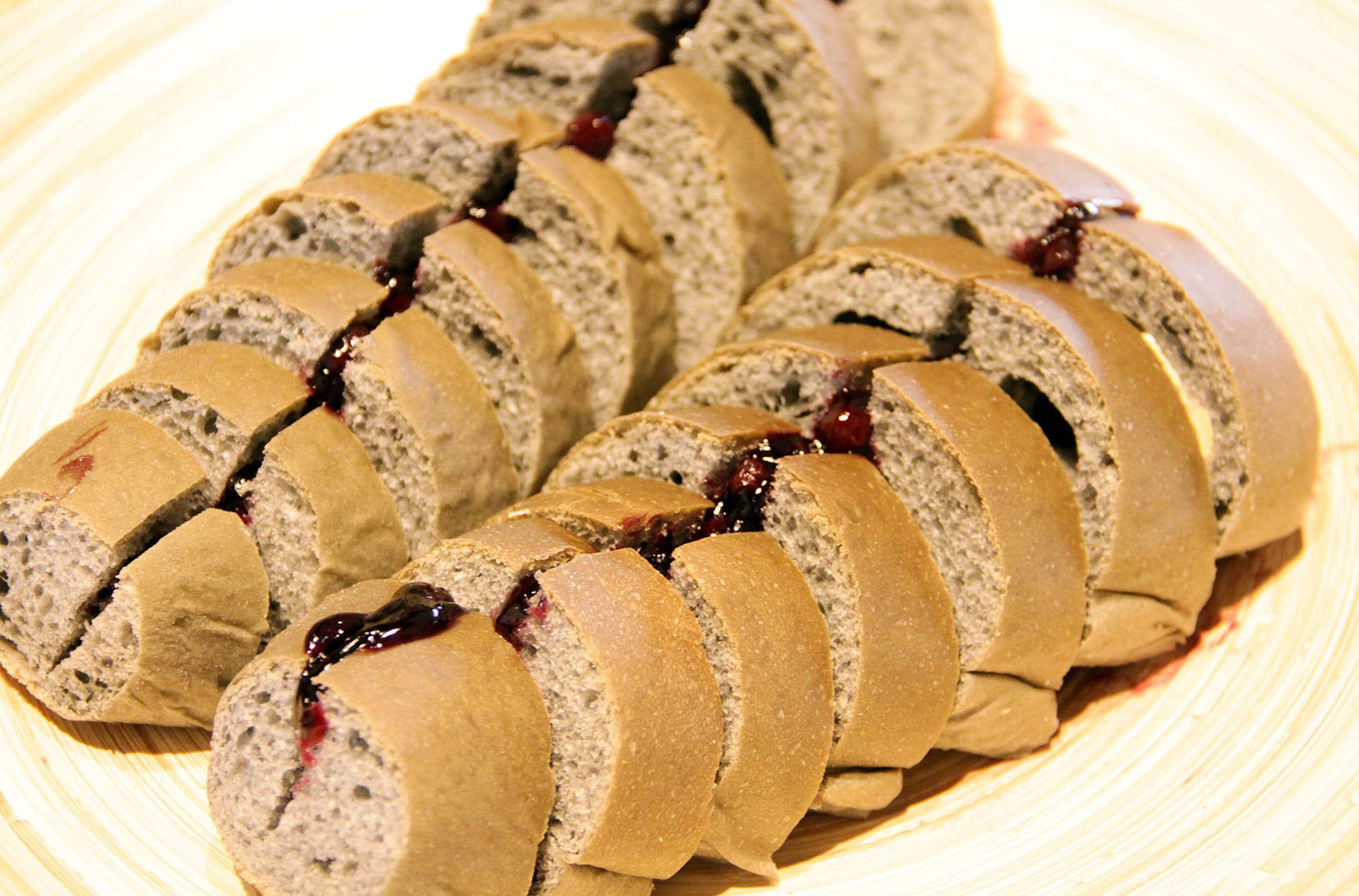 Eine Brotsemmel, geteilt und mit Marmelade gefüllt.