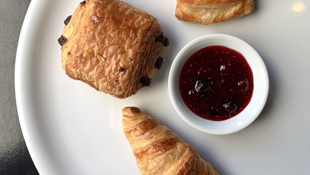 Une assiette avec trois pâtisseries et un petit bol de confiture.